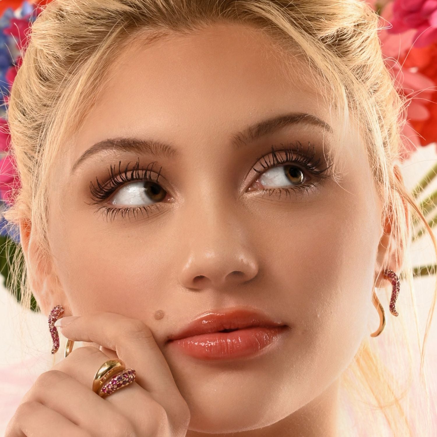 Close-up of a woman with decorative earrings and ring, with flowers in the background
